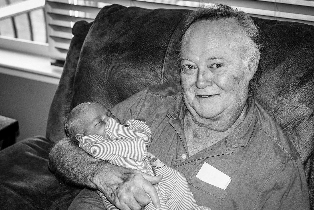 Ray Harrison holding a newborn grandchild